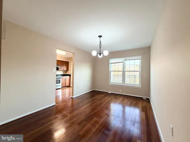 an empty room with wooden floor chandelier and windows