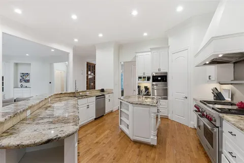a large kitchen with kitchen island a sink stove and white cabinets