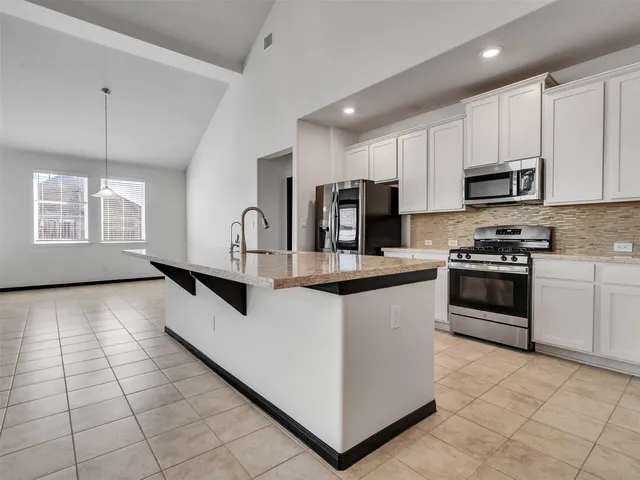 an empty room with a chandelier fan and windows