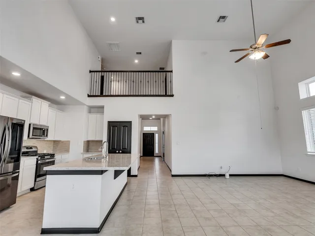 a view of a kitchen with a sink a refrigerator and white cabinets
