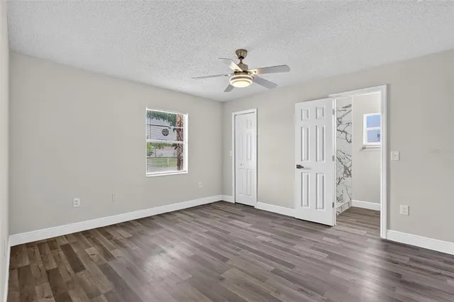 a view of empty room with wooden floor and ceiling fan