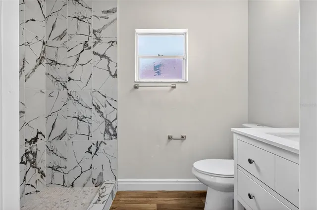 a bathroom with a granite countertop toilet a sink and a mirror