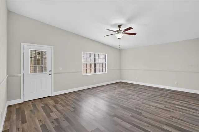 a view of an empty room with wooden floor and a window