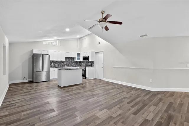 a view of an empty room with wooden floor fireplace and a window