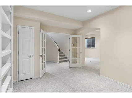 a view of an empty room with stairs and a living room
