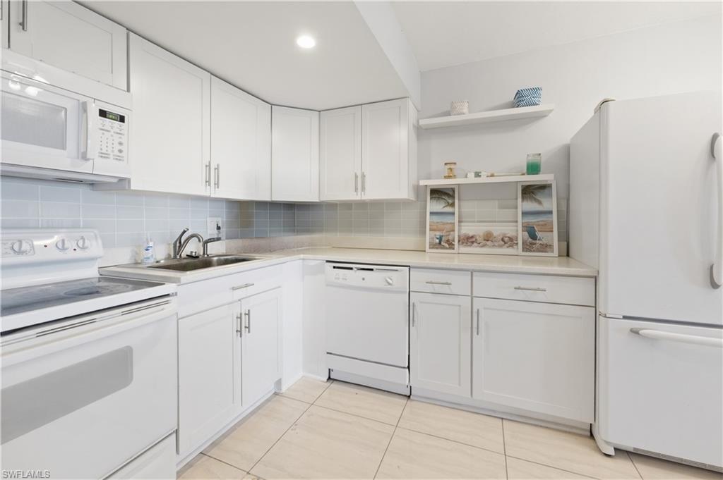 1 Bluebill Avenue, Unit 605 Naples, FL 34108 - Photo 15 of 20 Kitchen featuring white appliances, open shelves, white cabinetry, and light countertops