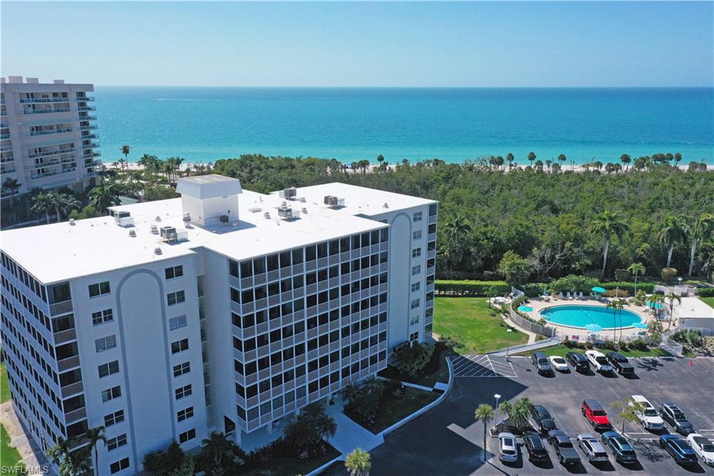 1 Bluebill Avenue, Unit 605 Naples, FL 34108 - Photo 2 of 20 Drone / aerial view of a pool area and a nearby body of water