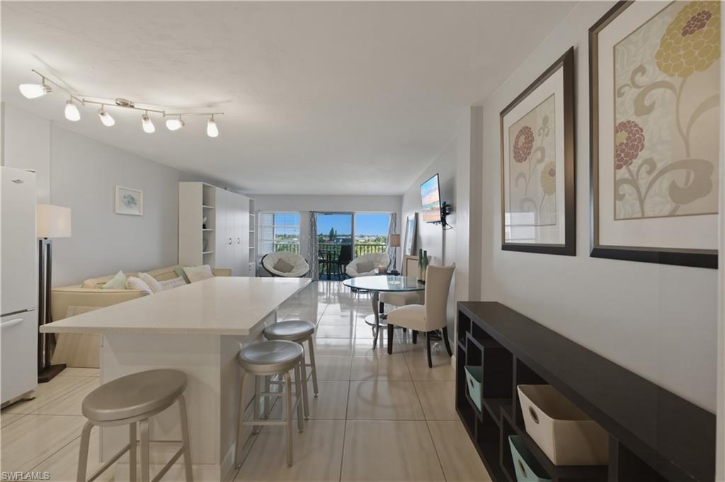 1 Bluebill Avenue, Unit 605 Naples, FL 34108 - Photo 7 of 20 Kitchen featuring a kitchen breakfast bar, freestanding refrigerator, a center island, and light tile patterned floors