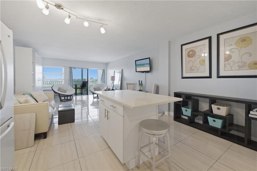 1 Bluebill Avenue, Unit 605 Naples, FL 34108 - Photo 20 of 20 Kitchen with a center island, a breakfast bar area, open floor plan, and white cabinetry
