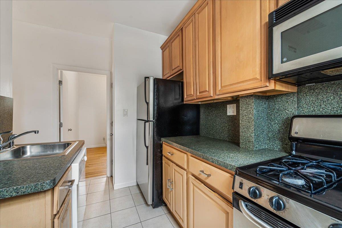 21-37 33rd Street, Unit 3D Queens, NY 11105 - Photo 11 of 15 a kitchen with stainless steel appliances granite countertop a sink stove and refrigerator