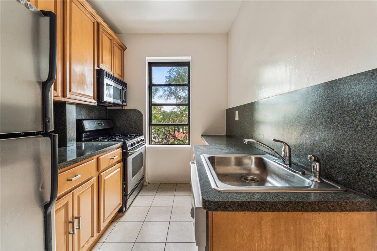 21-37 33rd Street, Unit 3D Queens, NY 11105 - Photo 10 of 15 a kitchen with stainless steel appliances granite countertop a sink stove and a refrigerator