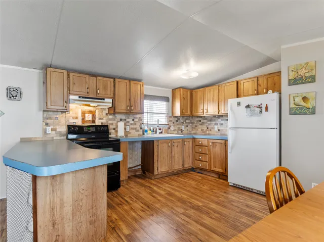 a kitchen with a refrigerator a stove a sink and white cabinets with wooden floor