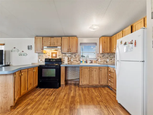 a kitchen with granite countertop a refrigerator stove top oven and sink