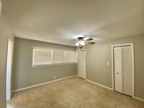 an empty room with windows and chandelier fan