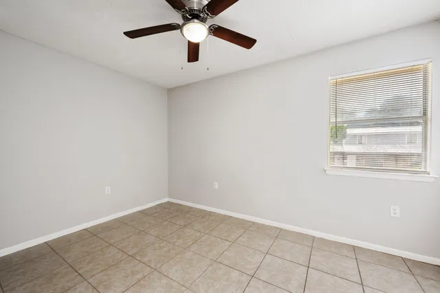 an empty room with windows and fan