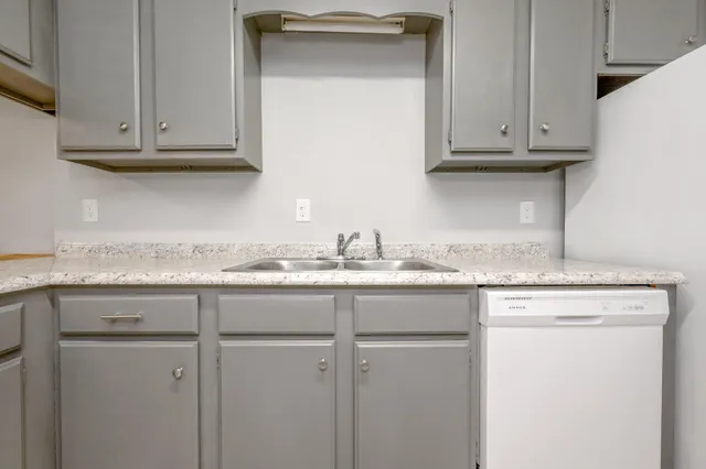 a kitchen with granite countertop white cabinets and a sink