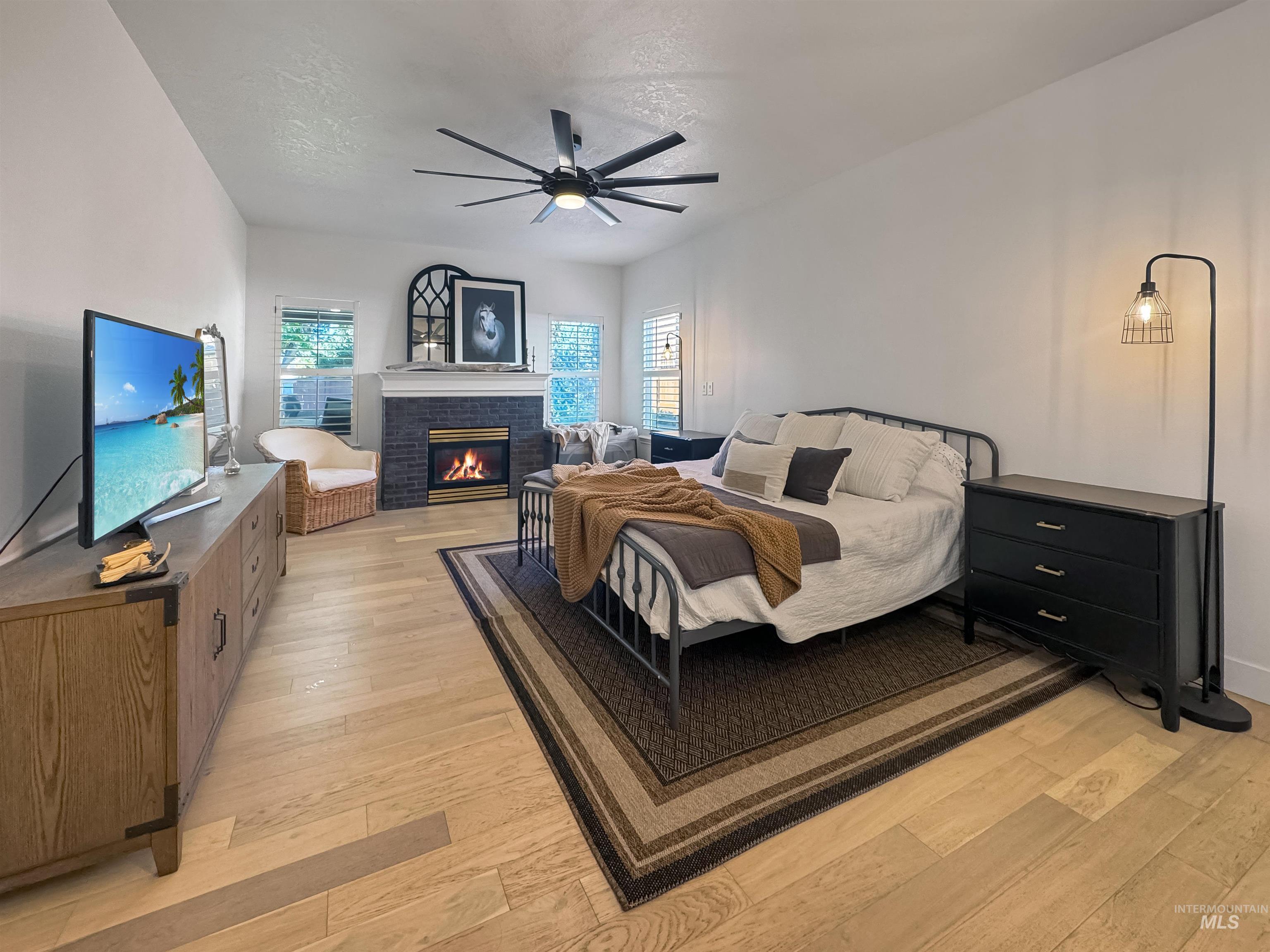 3917 North Waterloo Way Boise, ID 83713 - Photo 11 of 24 Spacious room featuring wood-finish flooring, a fireplace with a dark stone surround, and a ceiling fan with integrated lighting