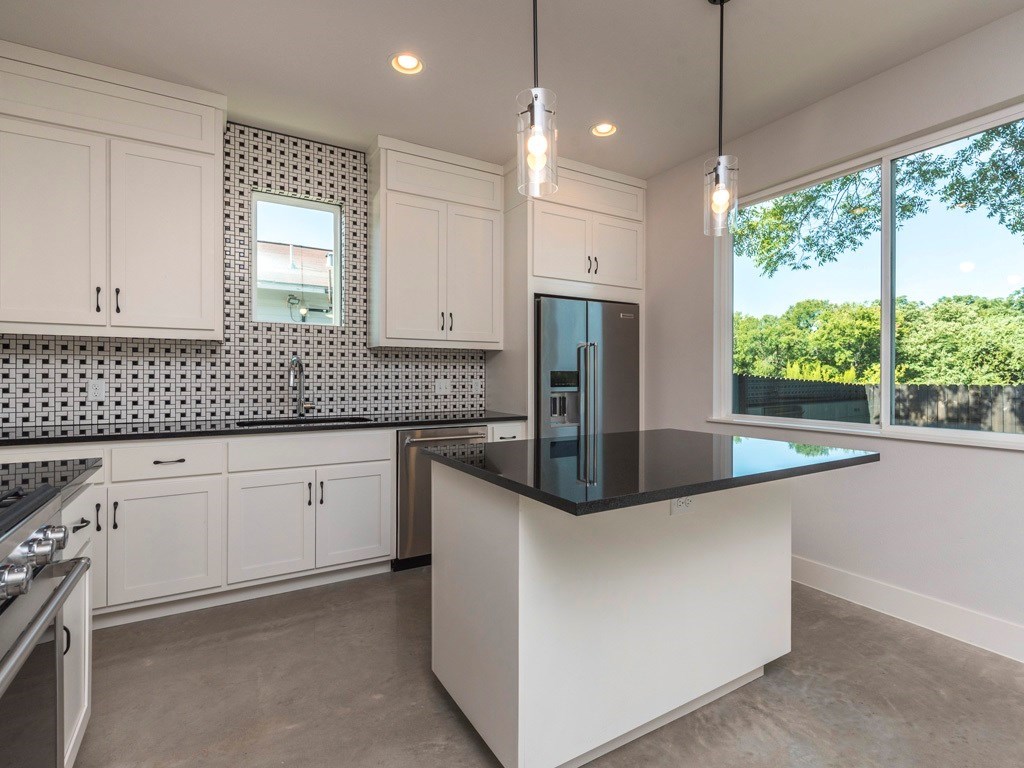 1182 Ridgeway Drive, Unit A Austin, TX 78702 - Photo 9 of 27 Kitchen with finished concrete floors, high end appliances, white cabinets, and tasteful backsplash