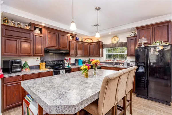 a kitchen with granite countertop a sink a stove a microwave cabinets and a window