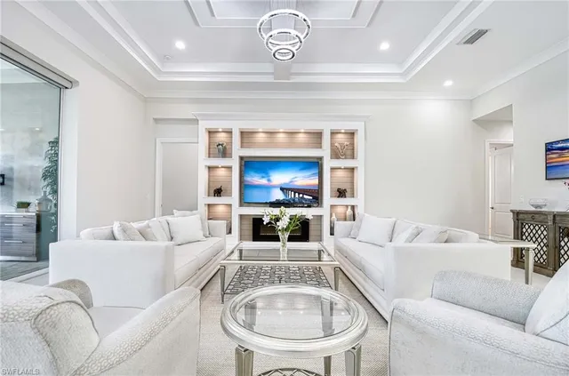 a living room with furniture kitchen view and a chandelier