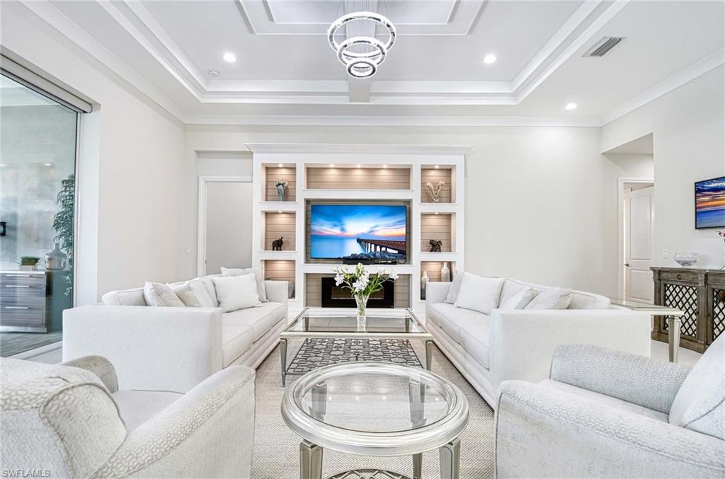 6159 Rodney Bay Lane Naples, FL 34113 - Photo 10 of 50 a living room with furniture a fireplace and a chandelier
