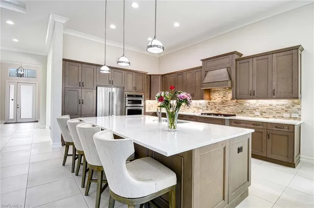a kitchen with stainless steel appliances kitchen island granite countertop a table chairs and a refrigerator