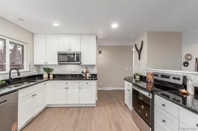 a kitchen with stainless steel appliances granite countertop a stove a sink and a microwave