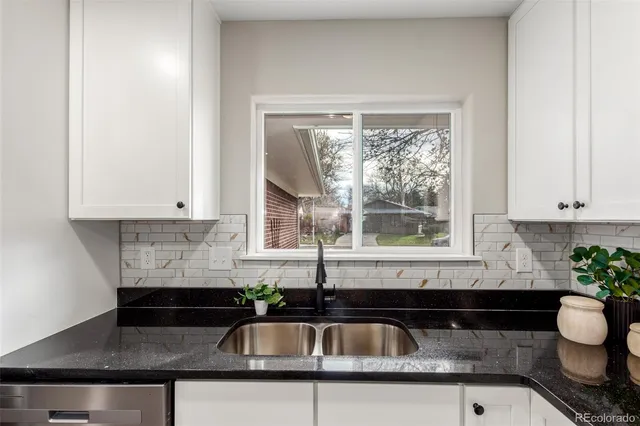 a kitchen with granite countertop white cabinets white appliances and a sink