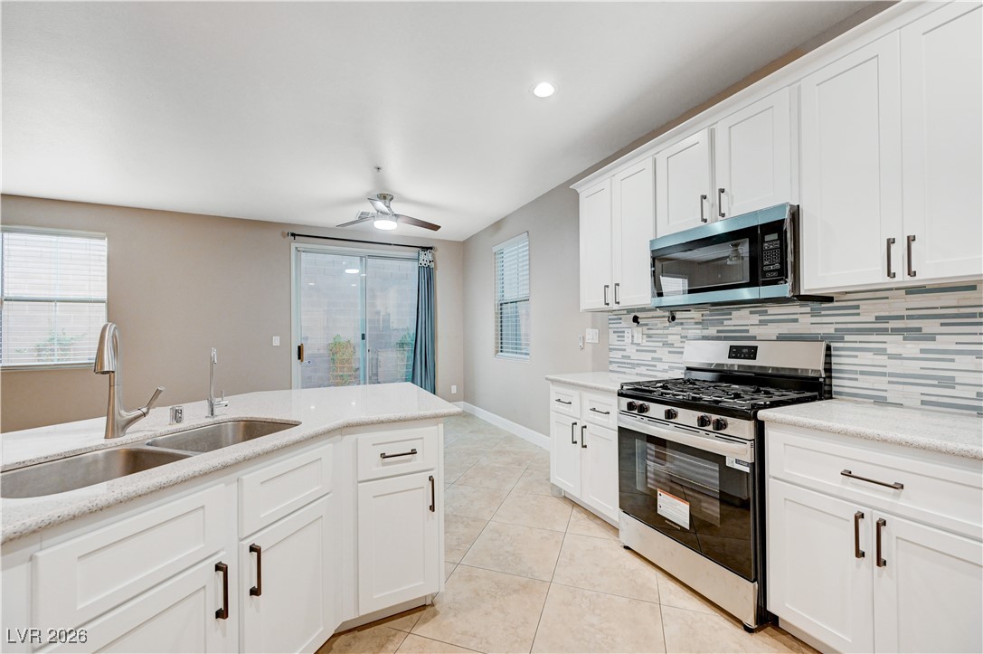 645 Monument Point Street Henderson, NV 89002 - Photo 20 of 54 Kitchen featuring stainless steel appliances, white cabinets, light tile patterned floors, a ceiling fan, and recessed lighting