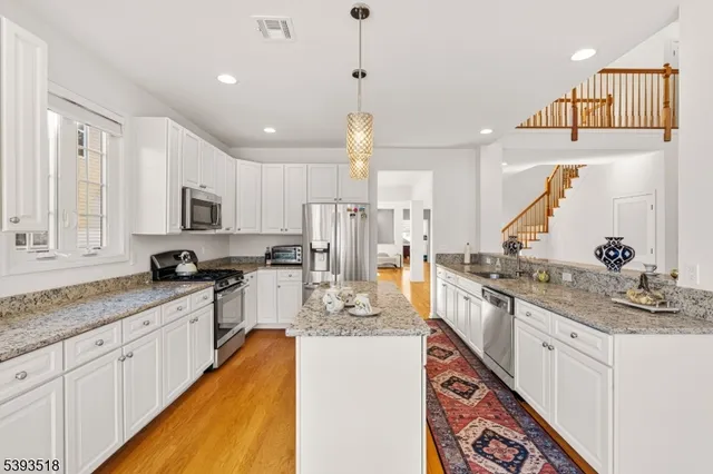 a large kitchen with stainless steel appliances kitchen island granite countertop a sink and cabinets