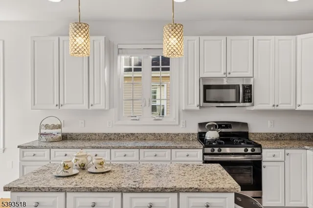 a kitchen with granite countertop a sink stainless steel appliances and white cabinets