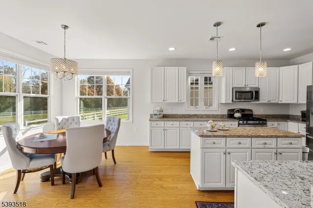 a kitchen with kitchen island granite countertop a table chairs sink and cabinets