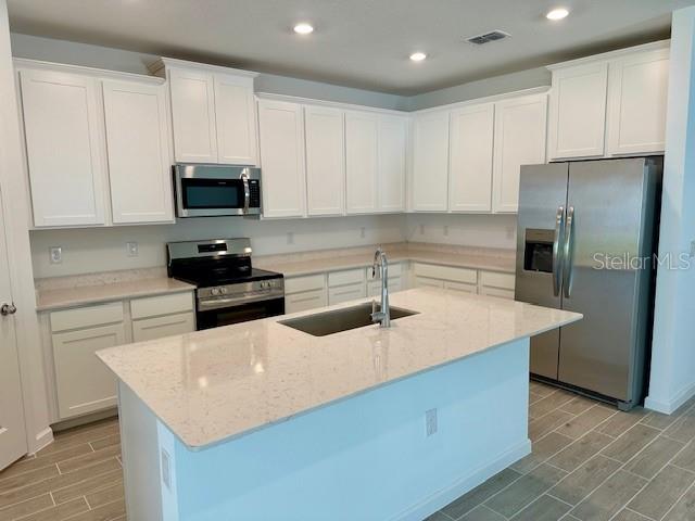 4511 Northwest 14th Loop Ocala, FL 34482 - Photo 3 of 27 a kitchen with stainless steel appliances a sink a stove a microwave a sink a refrigerator and cabinets