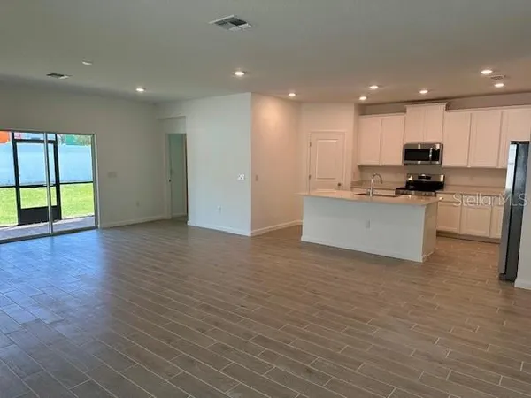 a view of kitchen with kitchen island wooden floors and stainless steel appliances