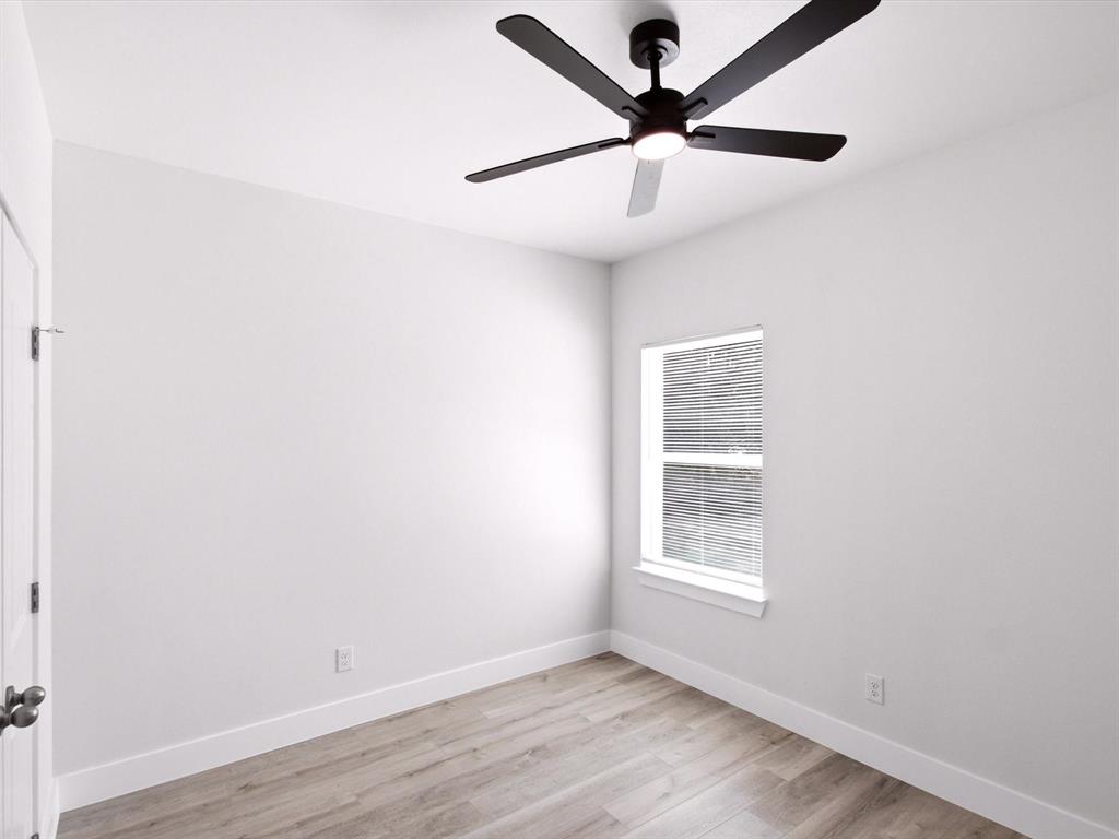 105 Oak Ridge Road Mabank, TX 75156 - Photo 15 of 34 Neutral paint palette with wood-finish flooring, a window with blinds, a white door, and a ceiling fan with integrated lighting