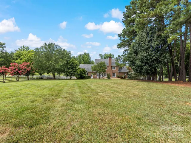 a front view of a house with a garden and trees