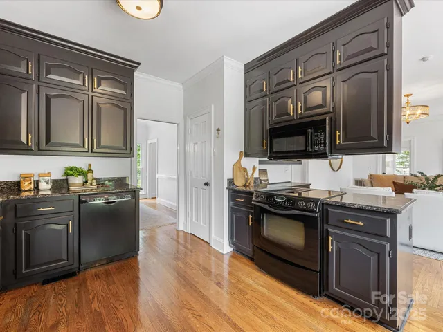a kitchen with stainless steel appliances granite countertop a stove a refrigerator a sink dishwasher a dining table and chairs with wooden floor