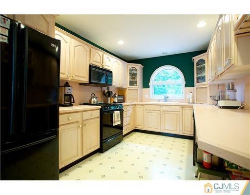 5 Beech Lane Edison, NJ 08820 - Photo 7 of 25 a kitchen with a sink a stove top oven a refrigerator with white cabinets and wooden floor
