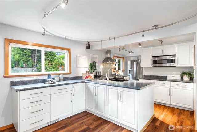 a kitchen with stainless steel appliances white cabinets a sink and a window