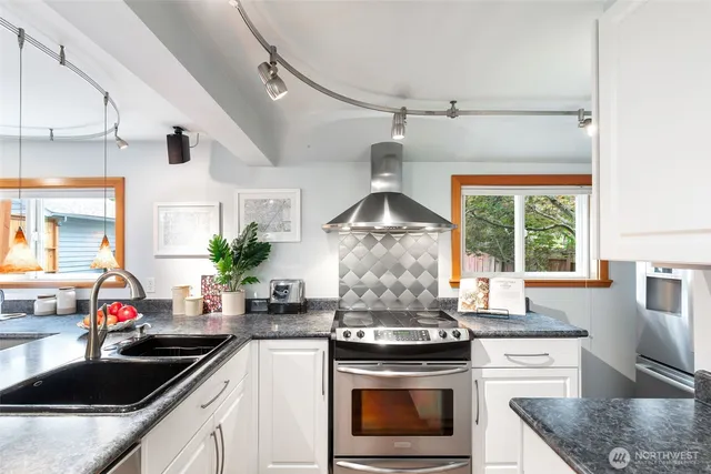 a kitchen with stainless steel appliances kitchen island a stove a sink and white cabinets
