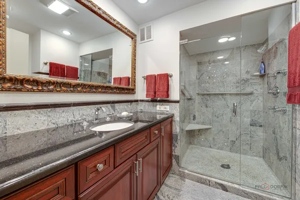 a bathroom with a granite countertop sink a mirror and shower