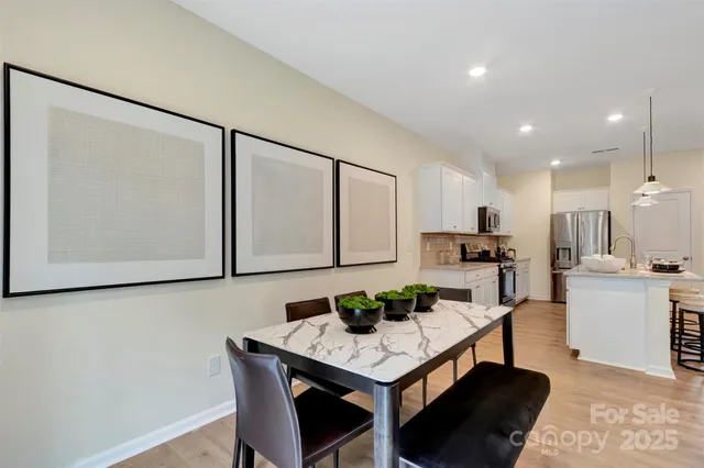 a kitchen with stainless steel appliances kitchen island granite countertop a table chairs sink and cabinets