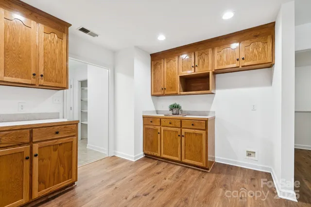 a kitchen with stainless steel appliances granite countertop a refrigerator a sink dishwasher and wooden cabinets with wooden floor