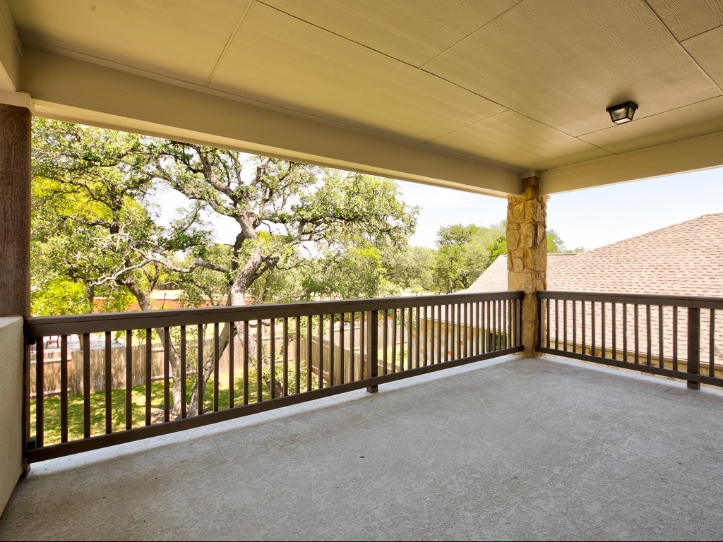 4303 Logan Ridge Drive Cedar Park, TX 78613 - Photo 23 of 24 Covered outdoor balcony featuring a textured concrete floor, dark wood railing, and a stone-clad support column