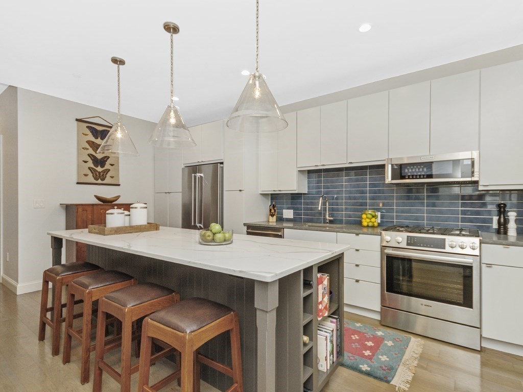 346 Congress Street, Unit 302 Boston, MA 02210 - Photo 11 of 22 a kitchen with a stove a refrigerator and a wooden floor