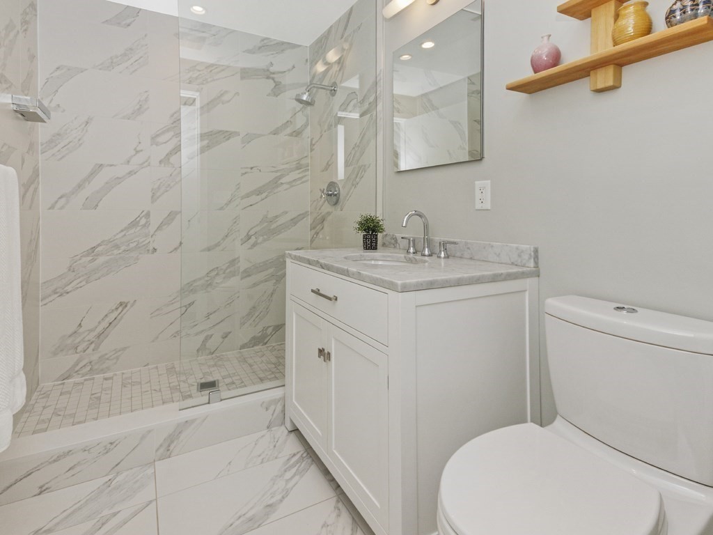 346 Congress Street, Unit 302 Boston, MA 02210 - Photo 15 of 22 a bathroom with a granite countertop toilet sink and mirror