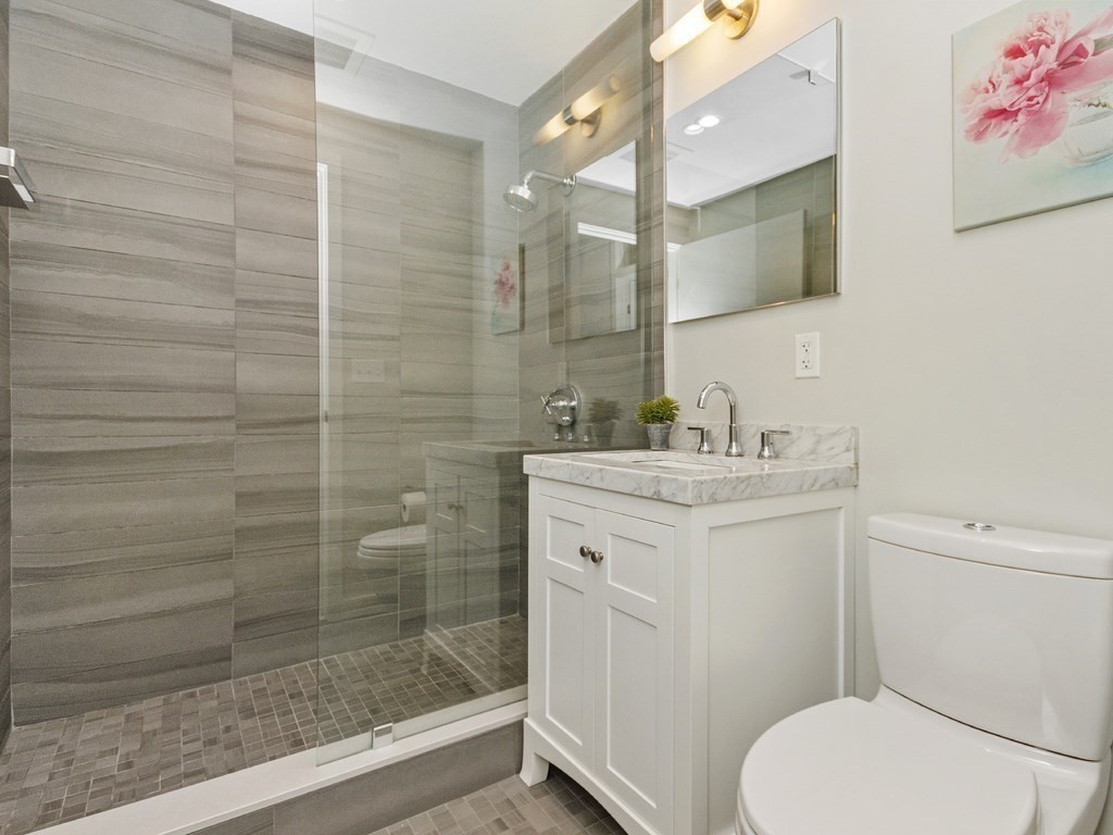 346 Congress Street, Unit 302 Boston, MA 02210 - Photo 17 of 22 a bathroom with a granite countertop sink toilet and shower