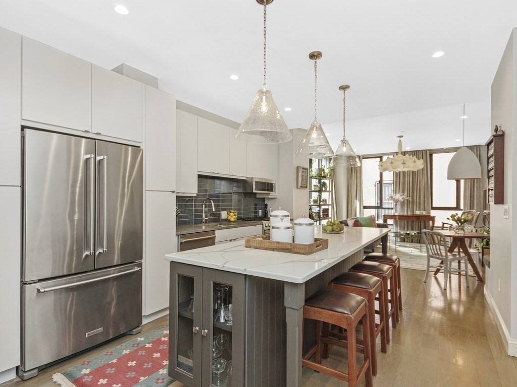 346 Congress Street, Unit 302 Boston, MA 02210 - Photo 7 of 22 a kitchen with stainless steel appliances granite countertop a refrigerator a sink dishwasher a oven a dining table and chairs with wooden floor