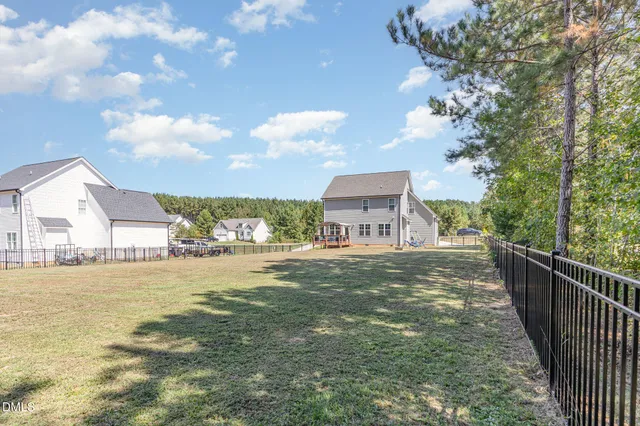 a view of a house with a yard and a large tree