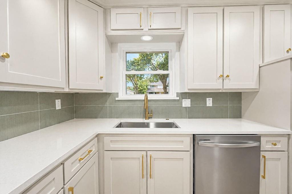 1904 Apollo Road Richardson, TX 75081 - Photo 15 of 40 White shaker-style cabinetry with gold-tone hardware, light-toned countertops, and a stainless steel dishwasher